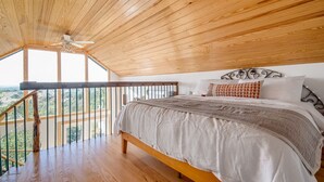 A bedroom with a wooden ceiling, a bed with white bedding, and a balcony with a railing. - Blue Sage No. 9 - The Stairway to Heaven (Fredericksburg)
