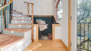 A modern interior with a spiral staircase, a built-in bench with cushions, and a view through a glass door. - Blue Sage No. 9 - The Stairway to Heaven (Fredericksburg)