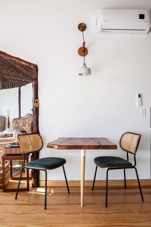 Un coin repas avec une table en bois et deux chaises, un luminaire suspendu et un appareil de climatisation fixé au mur.
