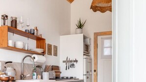 Une cuisine moderne avec des poutres en bois, un îlot central et des luminaires suspendus en osier.