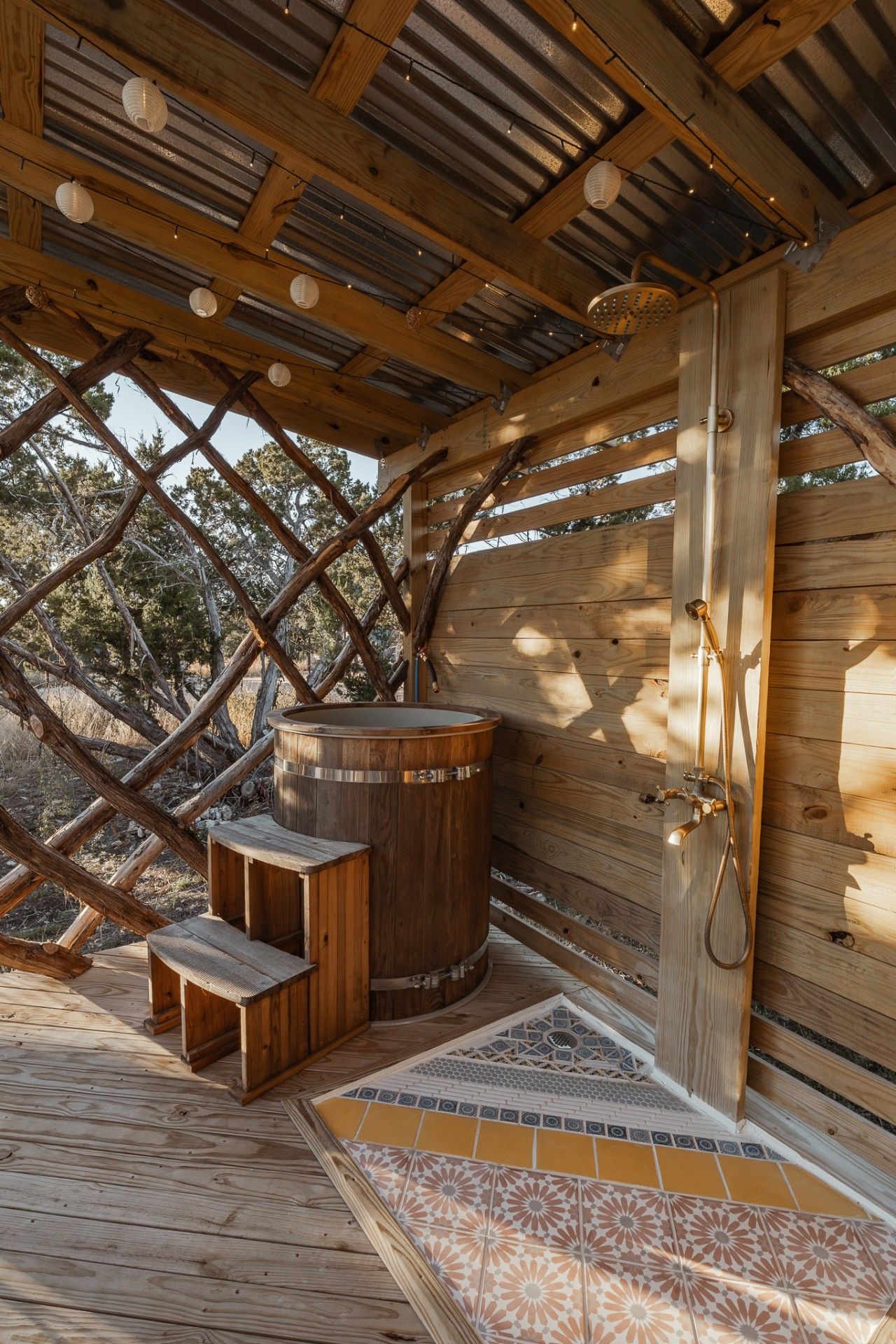 A wooden outdoor sauna with a hot tub, benches, and a shower area.