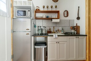 Una cocina compacta con microondas, pileta y un pequeño bote de basura.
