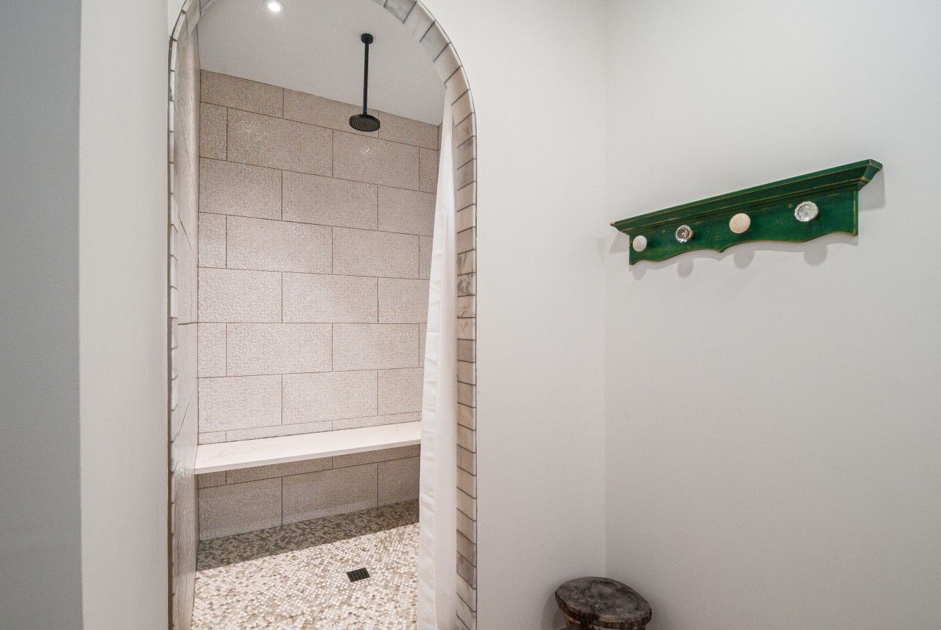 Un área de ducha con pared de azulejos, un banco y un estante verde.