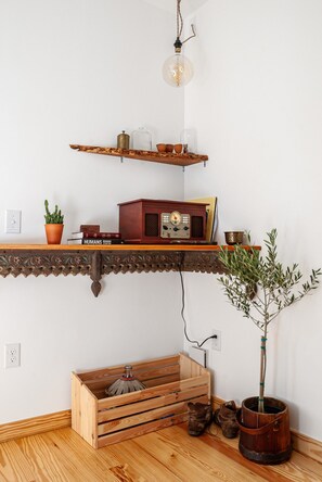 Un estante de madera con una radio antigua, una planta en maceta y una lámpara colgante.
