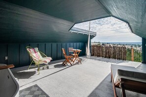 Un patio exterior con una mesa y sillas, vistas al paisaje y una valla de madera.