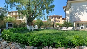 Un quartier résidentiel avec une pelouse verdoyante, des espaces de détente en plein air et un grand arbre.