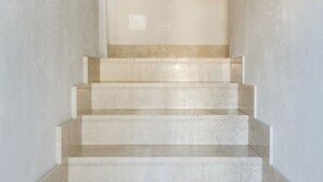 Un escalier en marbre menant vers le haut, avec un mur sobre au sommet.