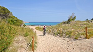 A sandy path leading to a beach with a cyclist. - Perleta - Apartment with sea views and communal pool in Mallorca (Capdepera)