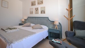A bedroom with a bed, bedside tables, a chair, and wall art. - Perleta - Apartment with sea views and communal pool in Mallorca (Capdepera)