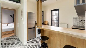 A compact kitchen with a built-in refrigerator, a washing machine, and a window with a view. - Vista: Spacious city centre home (Thessaloniki)