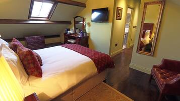 A bedroom with a large bed, a dresser, a television, and a mirror.