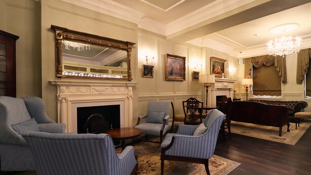 A traditional living room with a fireplace, multiple armchairs, a sofa, and a chandelier.
