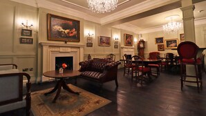 A formal dining room with a fireplace, leather sofa, dining table, and chairs.