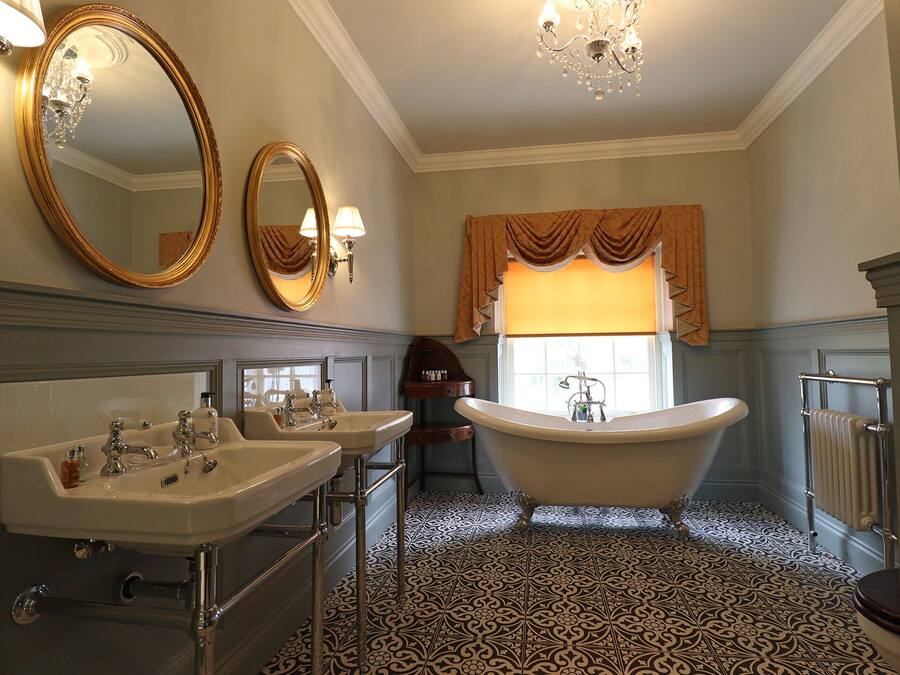 A bathroom with two sinks, a bathtub, and a large mirror.