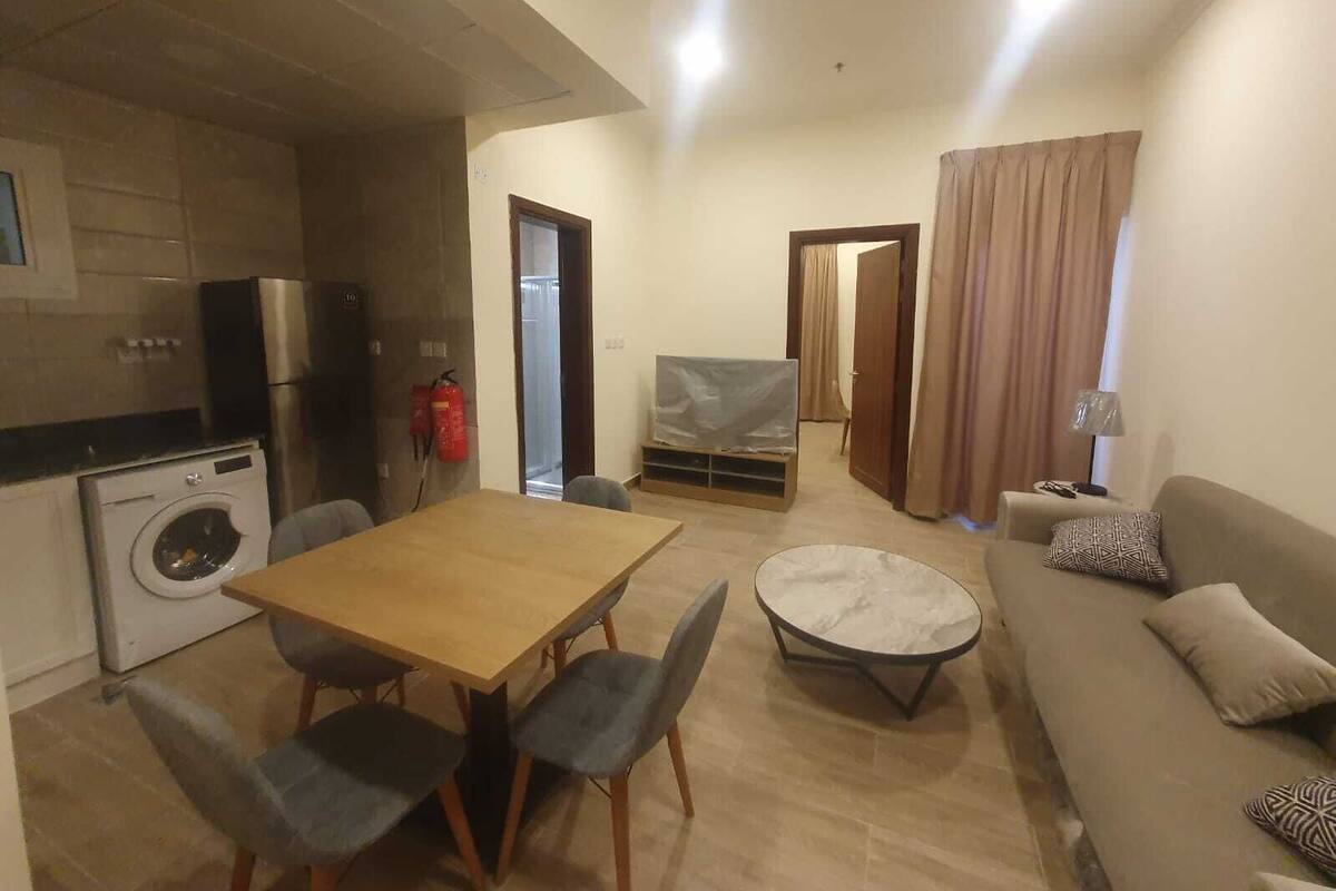 A compact living space with a dining area, a sofa, a small round table, and a washing machine.
