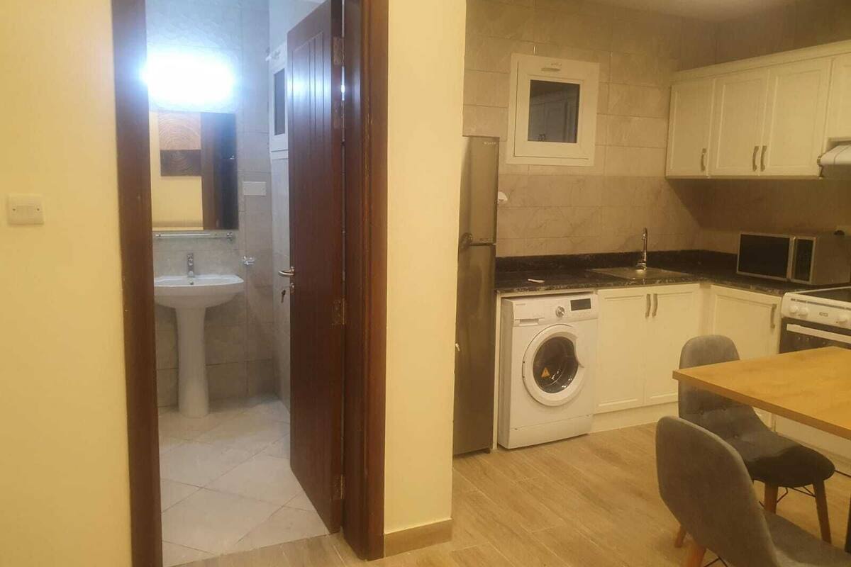 A compact kitchen with a washing machine, a sink, and a microwave.