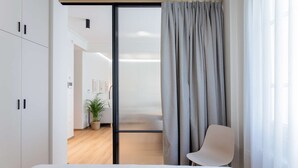 Une chambre moderne avec un lit, une chaise, une porte coulissante et une vue sur une autre pièce.