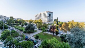 A modern multi-story hotel with a central courtyard, surrounded by lush greenery and a view of the sea. - City Moon: Chic apt with park and sea view (Thessaloniki)