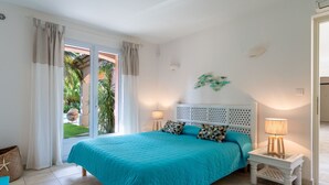 A bedroom with a large bed, a nightstand, a lamp, and a view of the outdoors. - Vacation home Indigo by Interhome (Grimaud)