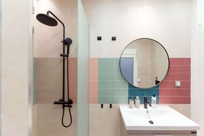 Une salle de bain avec une douche, un lavabo et un miroir.