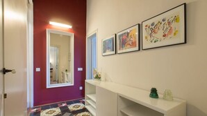 Ein Flur mit roter Wand, einem weißen Konsolentisch und drei gerahmten Kunstwerken.