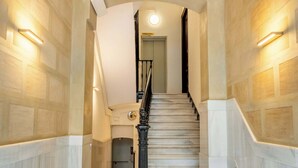 A grand staircase with a marble floor, flanked by walls with a textured pattern, leading to a door at the top. - Paseo de Gracia modern 4BD with Terrace (Barcelona)