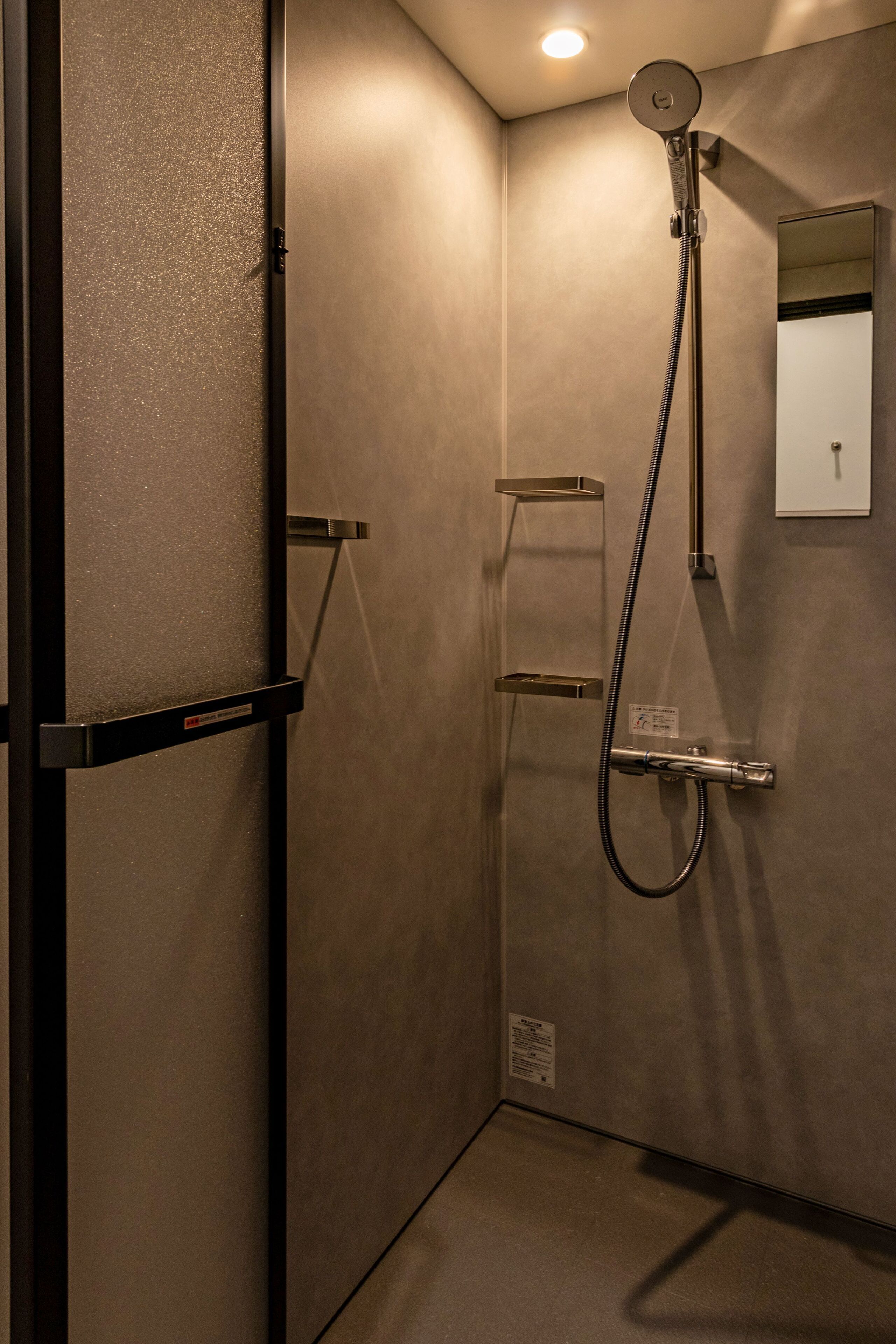 Een moderne badkamer met douche, spiegel en handdoekhouder.