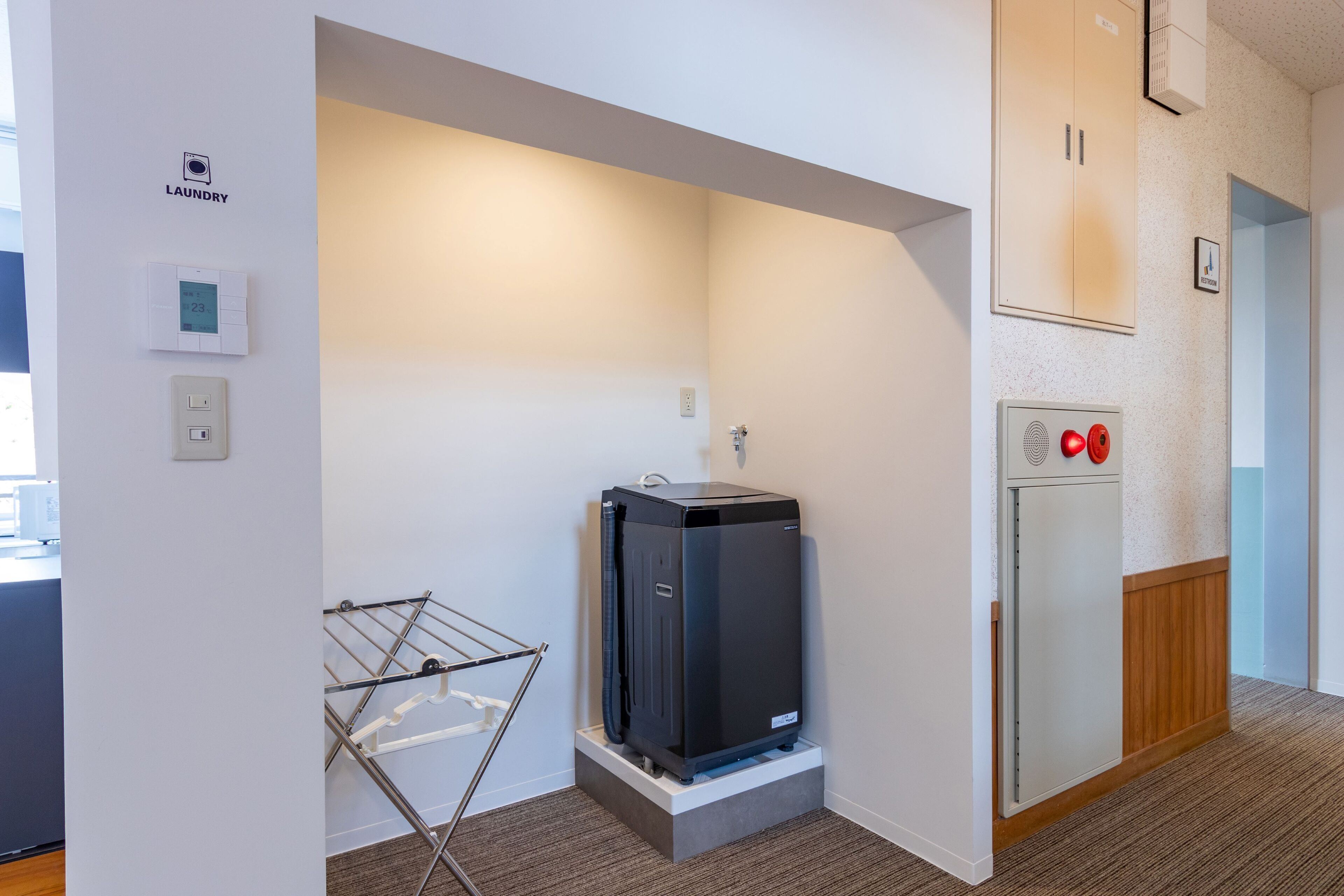 A compact laundry room with a washing machine, a dryer, and a drying rack.