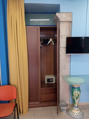 Una habitación con un armario de madera, microondas, televisión y un jarrón decorativo.