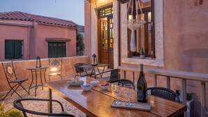 Un espacio de comedor al aire libre con una mesa de madera, sillas y una botella de vino.