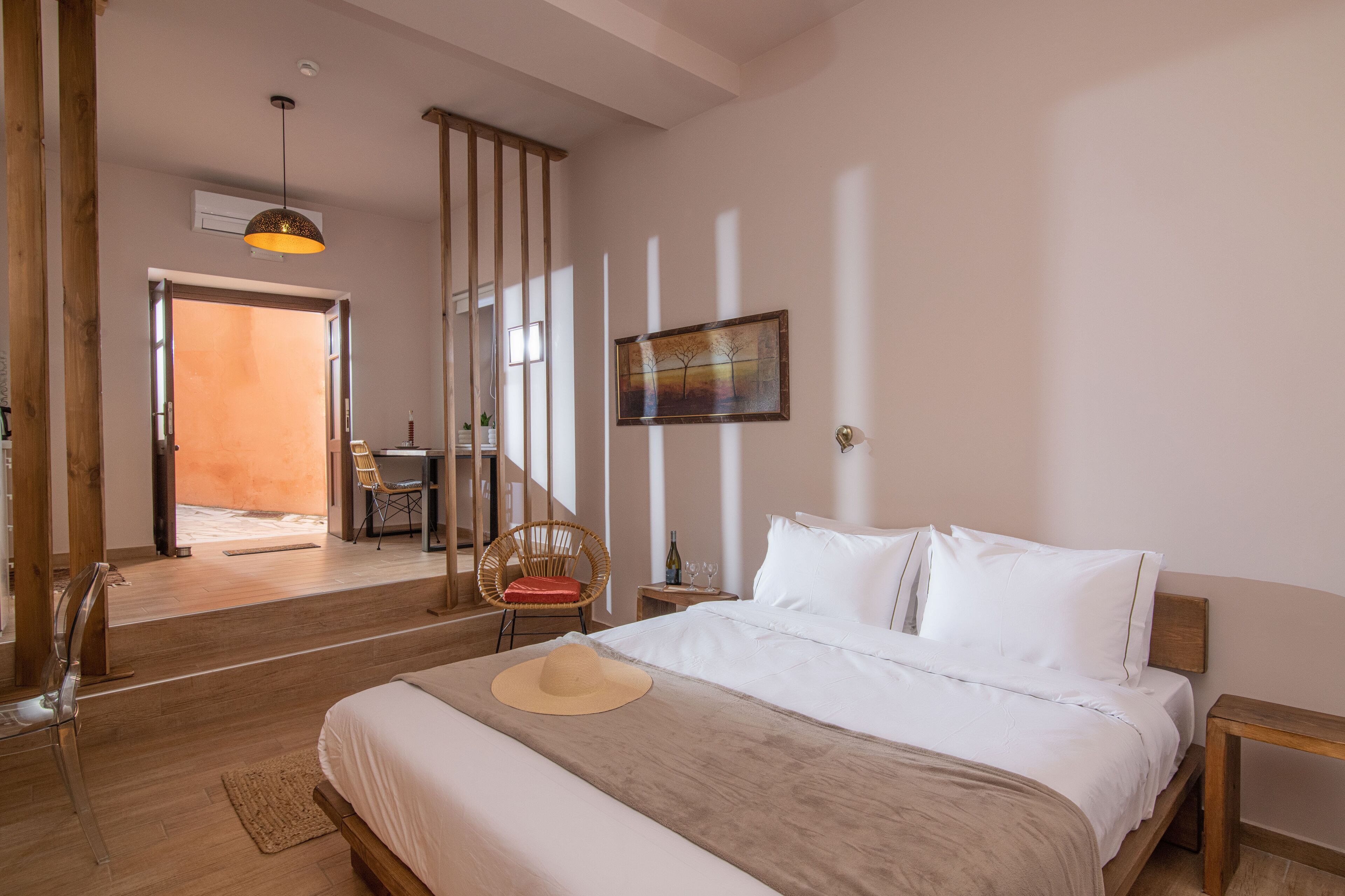 A bedroom with a bed, a chair, a small table, and a painting on the wall.