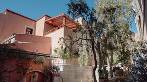 Un patio con una pérgola de madera, paredes de piedra y plantas en macetas.