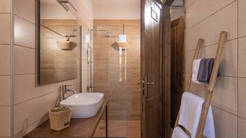 Een moderne badkamer met een grote spiegel, een witte wastafel en een douche.