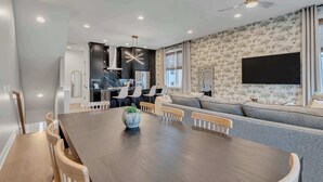 Un espace repas moderne avec une grande table en bois, des chaises et une plante en pot placée au centre.