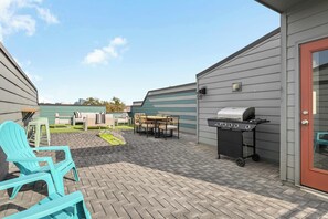 A patio area with outdoor furniture, a grill, and a door to a building.
