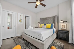 A bedroom with a bed, a ceiling fan, a nightstand, a lamp, and a framed picture on the wall.