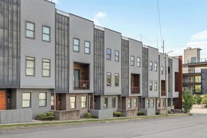A modern multi-story residential building with a uniform exterior, multiple balconies, and a brick foundation.