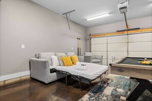 A compact room with a bed, a pool table, and a small seating area.