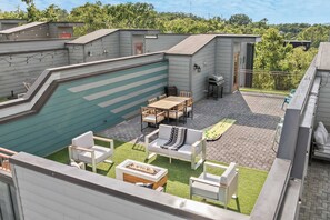 A rooftop patio with a pool, outdoor furniture, and a barbecue grill.