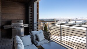 A balcony with a grill, seating area, and a view of a snowy landscape. - Apex Ski In/Out Canyons Village Beautiful 3 Bedroom, Private Hot Tub, Community Pool (Park City)
