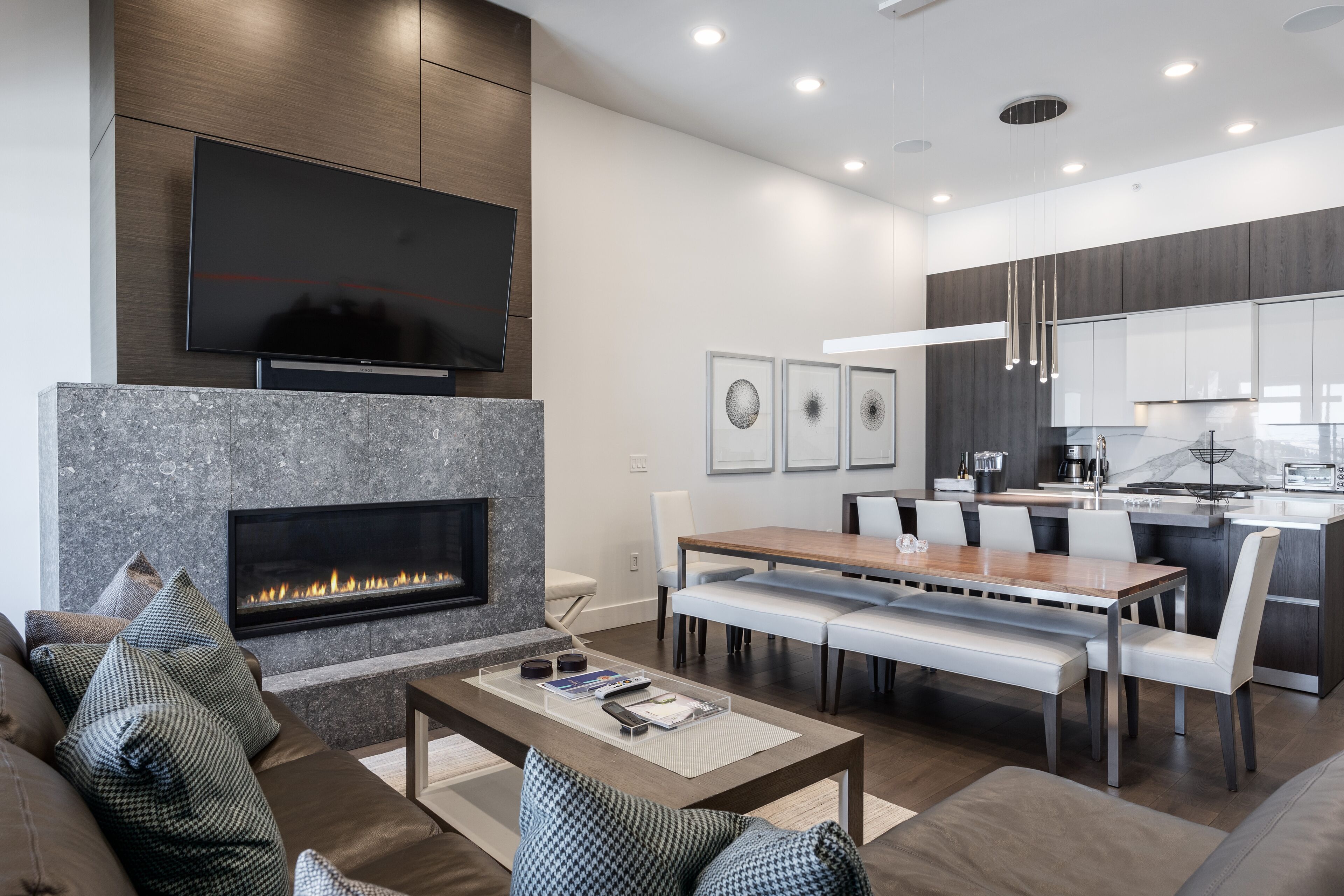 Una sala de estar moderna con chimenea, un televisor de pantalla plana montado encima y una zona de comedor con un banco.