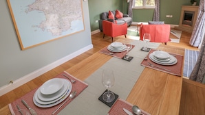 Un comedor con una mesa dispuesta para cuatro, un mapa en la pared y un sofá al fondo.