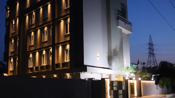 Un bâtiment moderne à plusieurs étages, doté de balcons et caractérisé par une entrée imposante avec une allée bordée de portails.