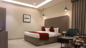 Une chambre d’hôtel moderne avec un grand lit, un bureau, une chaise et une petite table.