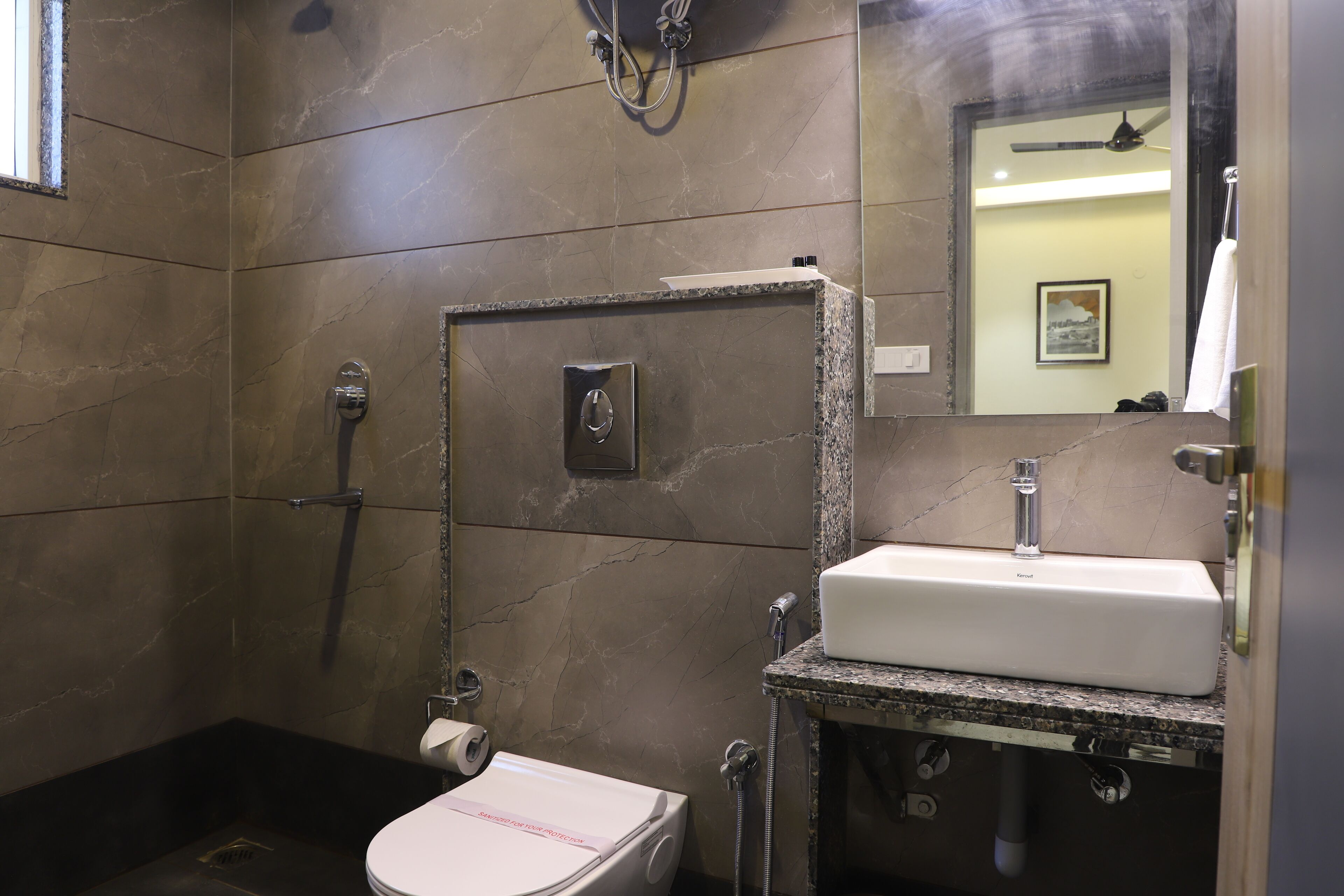 A bathroom with a toilet, a sink, a shower, and a mirror.