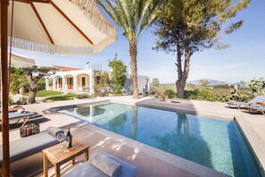 Relax by the rectangular pool surrounded by a serene garden and a villa with a covered patio.