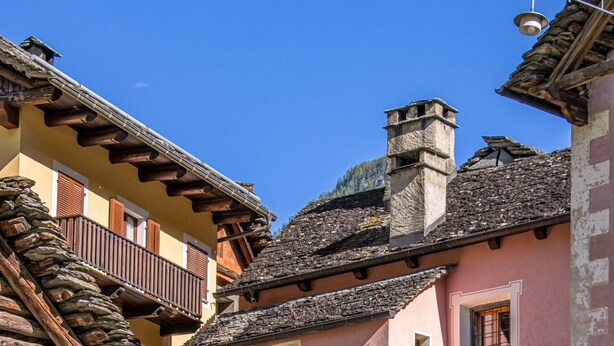 Un bâtiment traditionnel avec une façade rose, des murs en pierre et un balcon en bois.
