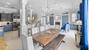 Uma cozinha ampla com eletrodomésticos modernos, uma sala de jantar com mesa de madeira e uma escada que dá acesso a um andar superior.