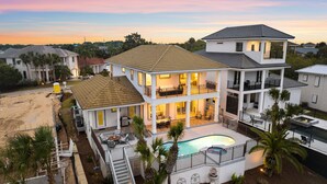 Uma casa com vários andares, um amplo deck, piscina e escadaria que dá acesso aos níveis superiores.