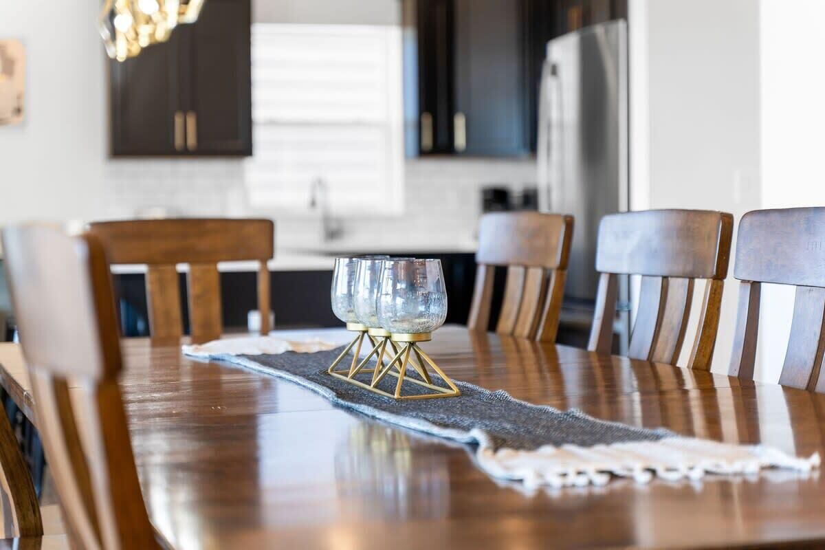 Une table à manger avec un centre de table en verre, des chaises en bois et un tapis foncé.